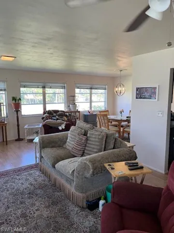 Living room featuring ceiling fan with notable chandelier, a healthy amount of sunlight, and wood-type flooring