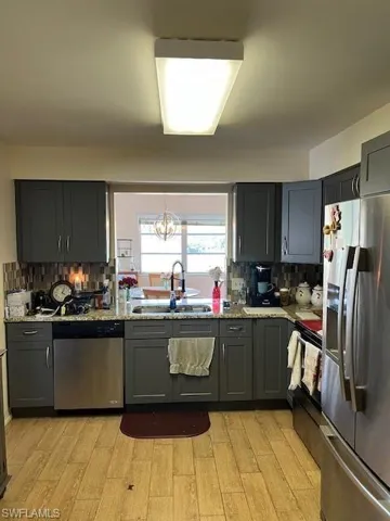Kitchen with dishwasher, backsplash, refrigerator, light wood-type flooring, and sink