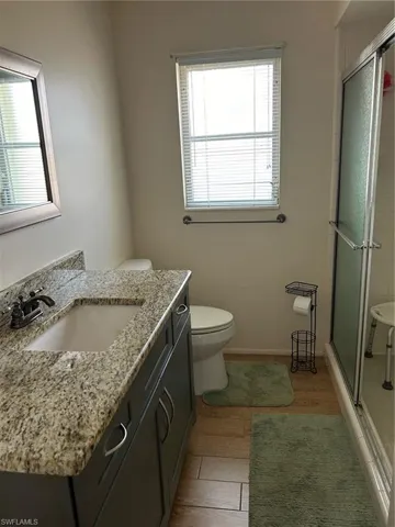 Bathroom with an enclosed shower, a wealth of natural light, toilet, and vanity