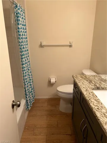 Full bathroom with shower / bath combo with shower curtain, vanity, toilet, and hardwood / wood-style floors