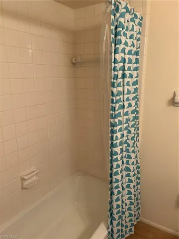 Bathroom with wood-type flooring and tiled shower / bath combo