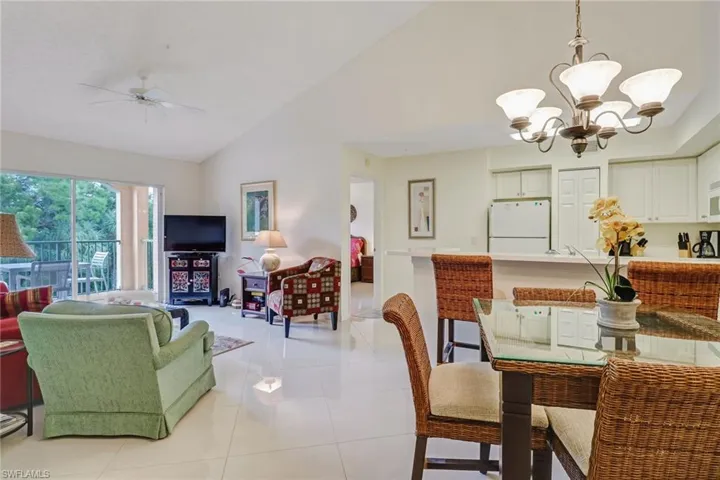 Dining area featuring light tile patterned floors, high vaulted ceiling, a chandelier, and ceiling fan