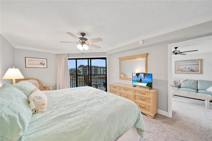 Carpeted bedroom featuring ceiling fan, crown molding, and access to exterior