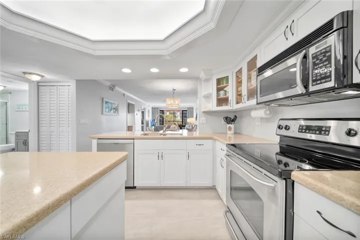 Kitchen with white cabinetry, sink, crown molding, decorative light fixtures, and stainless steel appliances