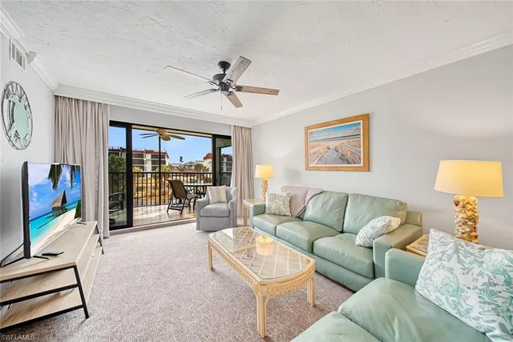 Carpeted living room with ornamental molding, a textured ceiling, and ceiling fan