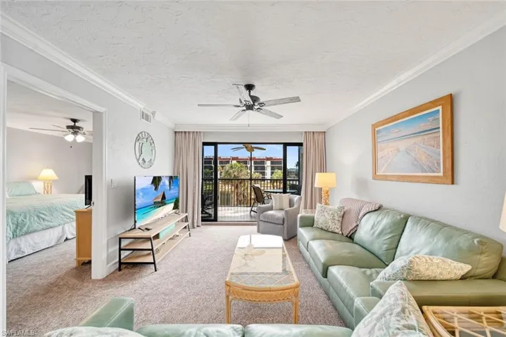 Carpeted living room featuring crown molding and ceiling fan
