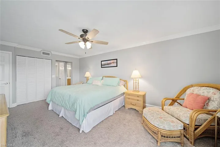 Carpeted bedroom featuring a closet, ornamental molding, and ceiling fan