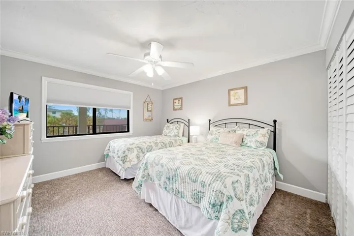 Carpeted bedroom featuring ornamental molding and ceiling fan
