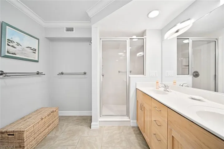 Bathroom featuring a shower with door, vanity, and crown molding