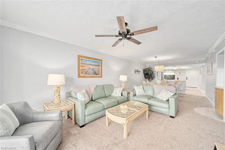 Carpeted living room with crown molding, a textured ceiling, and ceiling fan