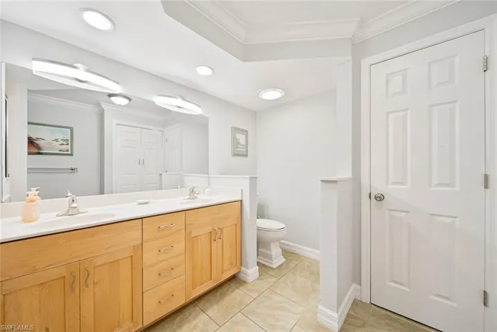 Bathroom featuring vanity, crown molding, and toilet