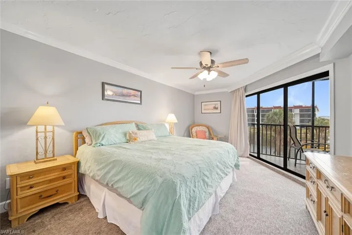 Carpeted bedroom with ceiling fan, access to outside, and ornamental molding