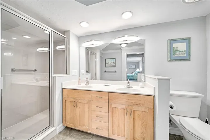 Bathroom with vanity, toilet, crown molding, and a shower with shower door