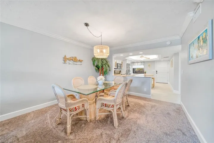 Dining area with sink, crown molding, light colored carpet, and ceiling fan