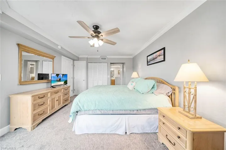 Bedroom with ceiling fan, light carpet, and crown molding