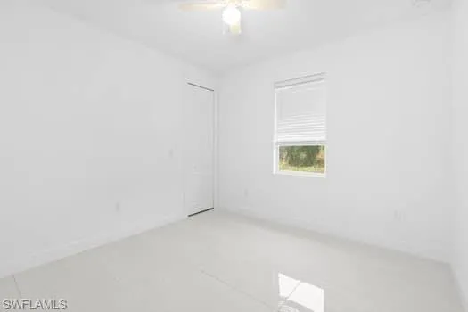 Tiled empty room featuring ceiling fan