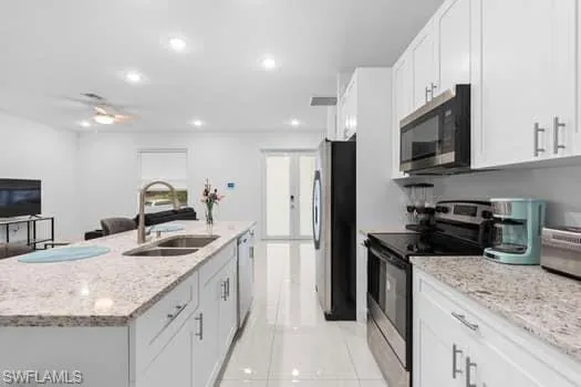 Kitchen with appliances with stainless steel finishes, white cabinetry, sink, a center island with sink, and light tile patterned flooring