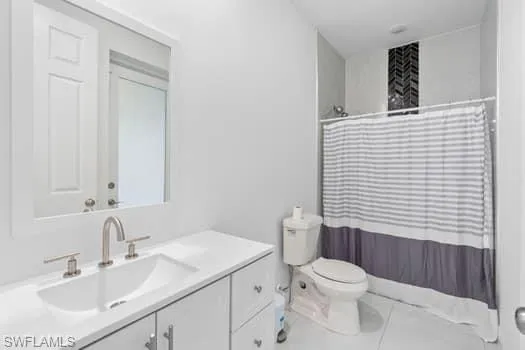 Bathroom with vanity, toilet, and curtained shower