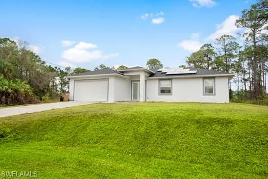 Ranch-style house with a garage, a front lawn, and solar panels