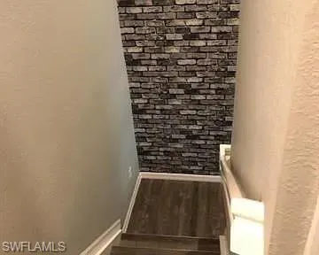 Stairway featuring wood finished floors and a textured wall