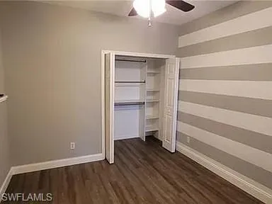 Unfurnished bedroom with dark wood-type flooring, ceiling fan, and a closet