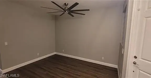 Empty room featuring dark wood-style flooring and a ceiling fan