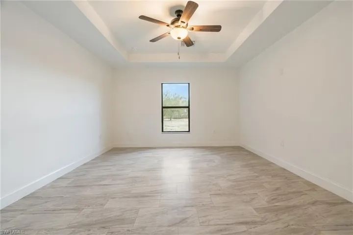 Empty room featuring a raised ceiling and ceiling fan