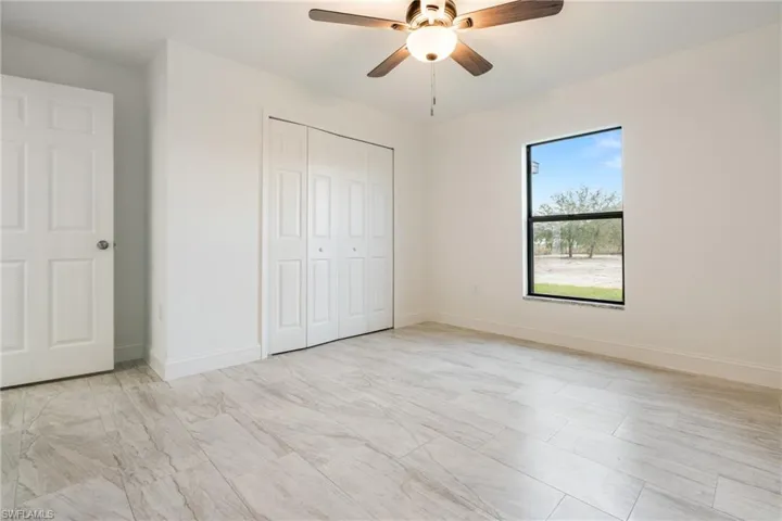 Unfurnished bedroom with ceiling fan and a closet