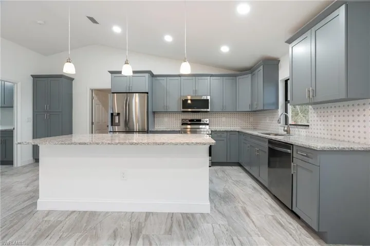 Kitchen with tasteful backsplash, pendant lighting, stainless steel appliances, gray cabinets, and a center island