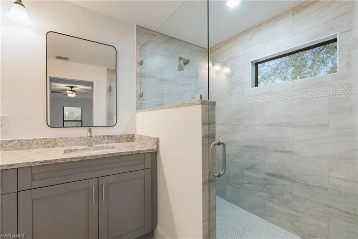 Full bathroom with healthy amount of natural light, a stall shower, vanity, and ceiling fan