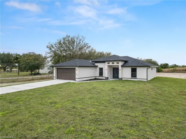 Back of property with a yard, roof with shingles, stucco siding, and a sunroom