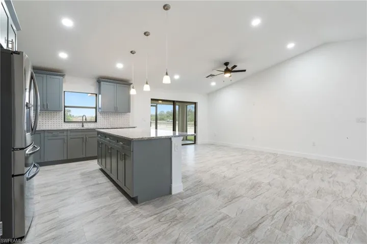 Kitchen with stainless steel fridge with ice dispenser, healthy amount of natural light, backsplash, decorative light fixtures, and recessed lighting