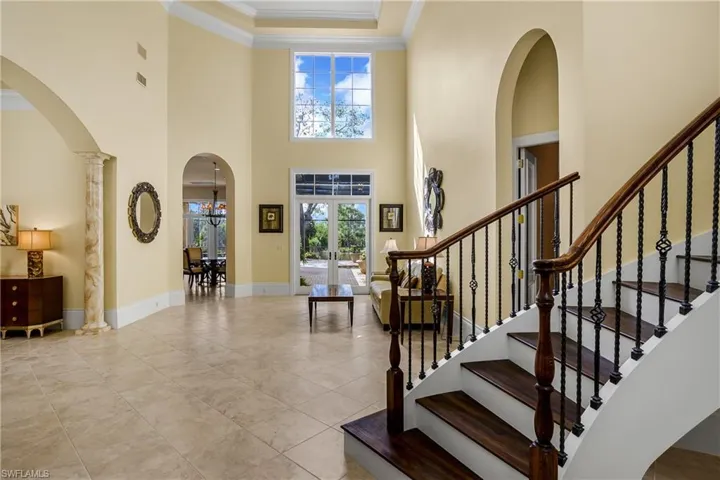 Foyer entry with view of lanai and sweeping curved stairway to the right. Dining room to left.