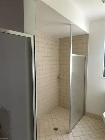 Full bath with toilet, a shower stall, and tile patterned floors