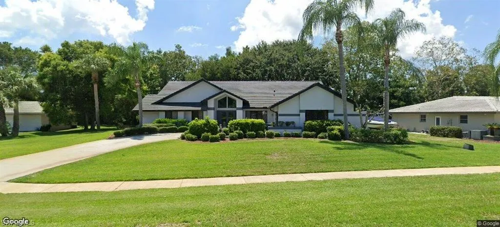 View of front of home featuring a front yard, concrete driveway, central AC, and a tiled roof