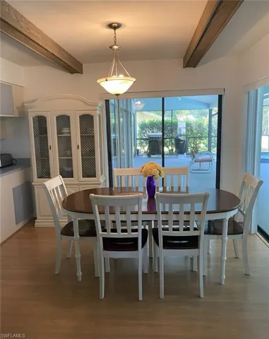 Dining room featuring wood finished floors, a wealth of natural light, and beamed ceiling
