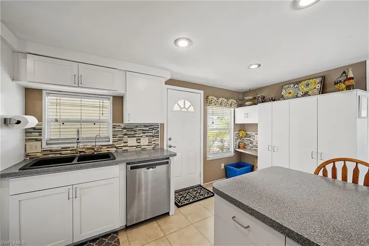 Kitchen with white cabinets, stainless steel dishwasher, light tile patterned floors, tasteful backsplash, and recessed lighting