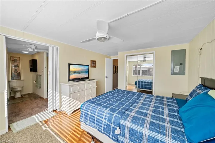 Bedroom featuring electric panel, carpet flooring, a closet, ceiling fan, and ensuite bath