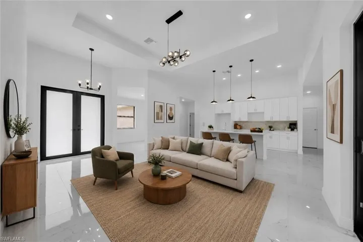 Spacious living area featuring high ceilings, large format tile flooring, and modern lighting fixtures