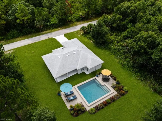 Expansive grounds showcase a modern residence with a crisp white exterior and pitched roofline, set on manicured lawn surrounded by mature tree lines