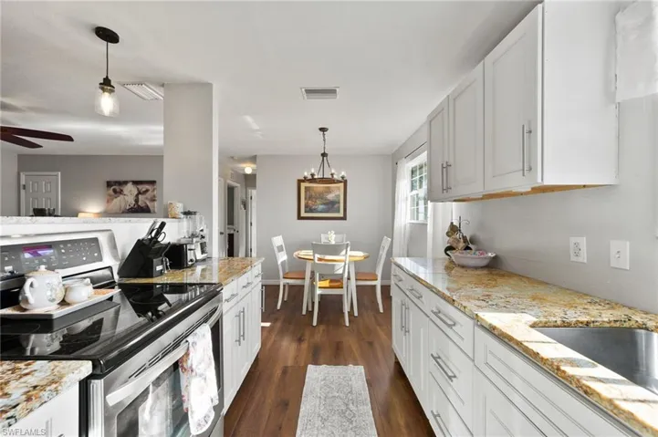 Kitchen featuring electric stove, visible vents, dark wood-style flooring, and pendant lighting
