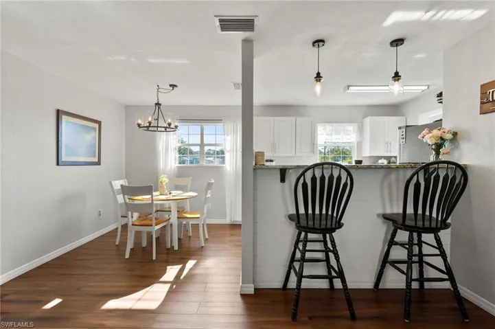Kitchen with visible vents, freestanding refrigerator, a kitchen bar, and a healthy amount of sunlight