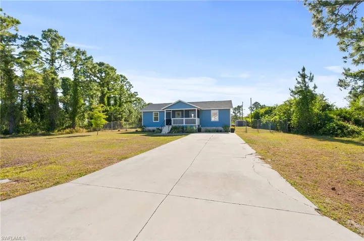 View of front of house featuring a front lawn, fence, and driveway