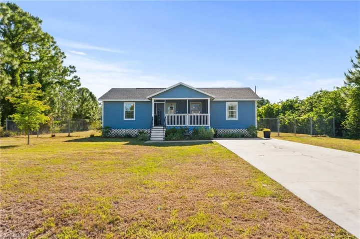 View of front of home with a sunroom, driveway, fence, and a front lawn