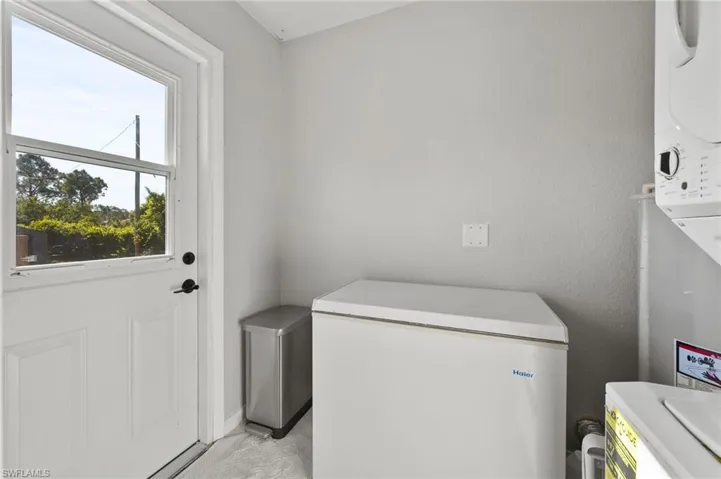 Clothes washing area with stacked washer and dryer and laundry area