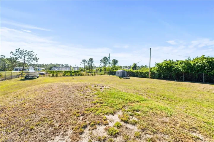 View of yard featuring an outbuilding, a shed, and fence