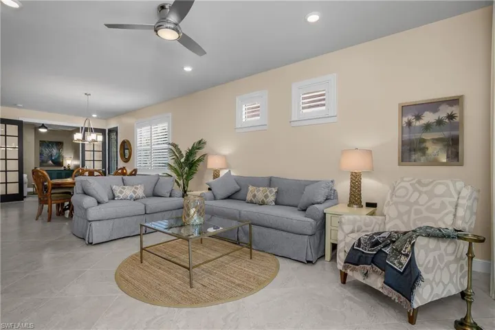 Living room featuring a ceiling fan, suspended lighting, and tile patterned floors