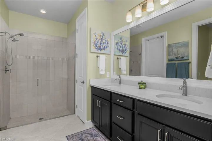 Full bath with double vanity and a ceramic detail walk-in shower