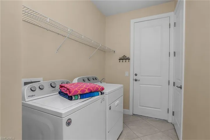 Laundry area with light tile patterned floors and washer and clothes dryer