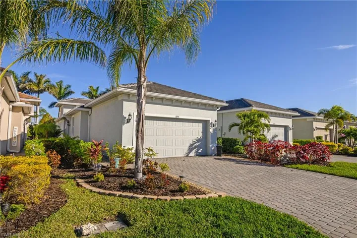 View of front facade featuring stucco siding, decorative driveway, and a garage